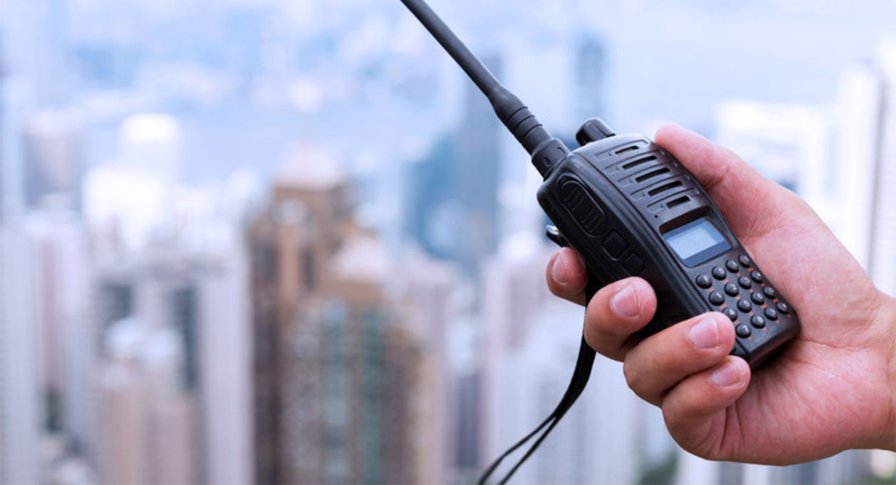 Man Holding a Small Two Way Radio | Two Way Radios for Security, Safety and Business - Fast Radios, Inc.